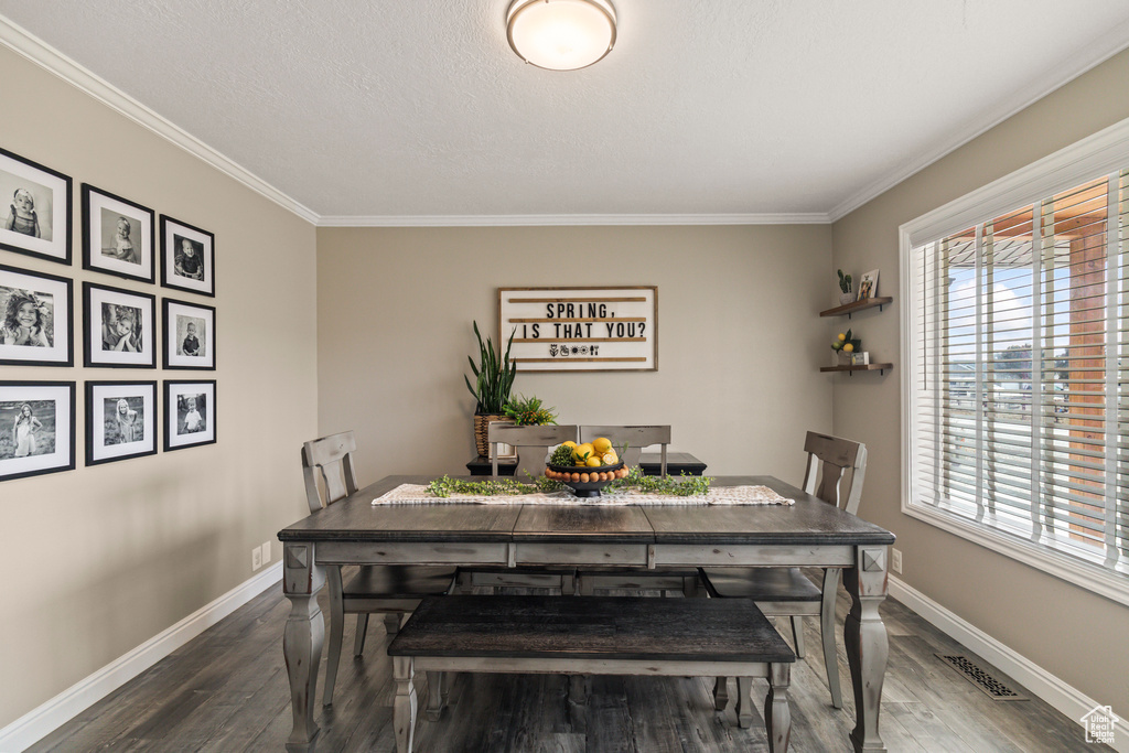 Dining space featuring baseboards, dark wood finished floors, and ornamental molding