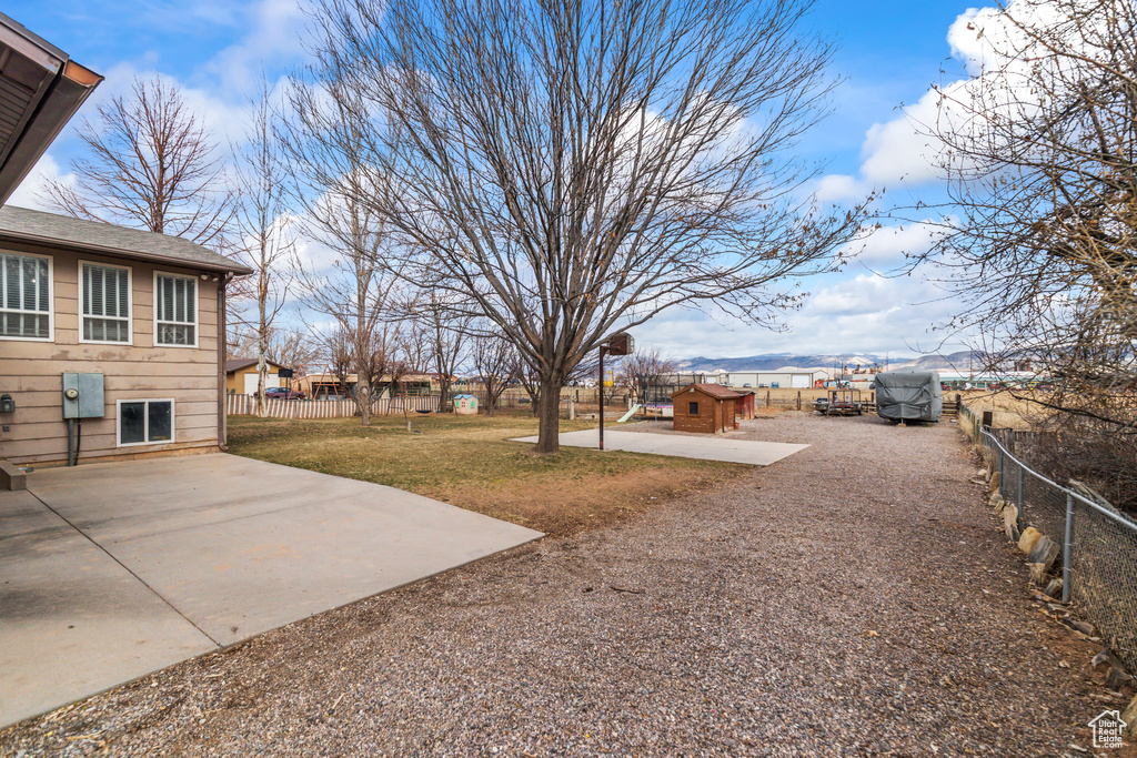 View of yard with driveway, a patio area, a fenced backyard, and an outdoor structure