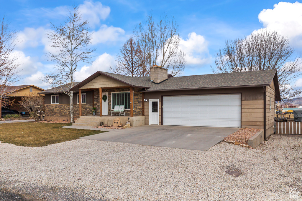 Single story home with a garage, driveway, a chimney, and a shingled roof