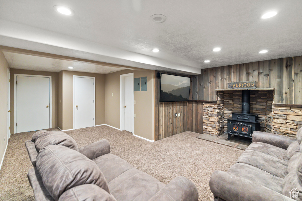 Carpeted living room featuring recessed lighting, a wood stove, wood walls, and a textured ceiling