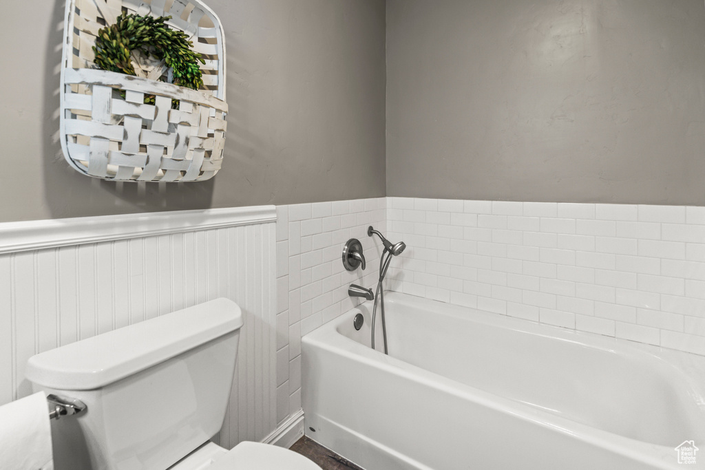 Full bath with a wainscoted wall, a garden tub, and toilet