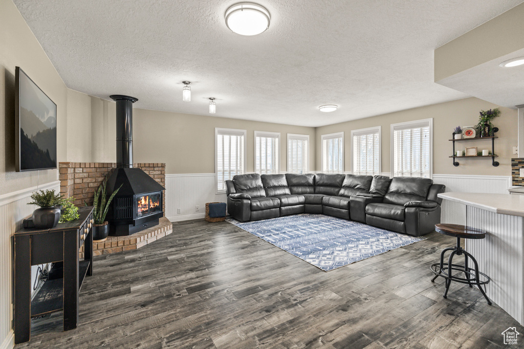 Living room with a wainscoted wall, a textured ceiling, and wood finished floors