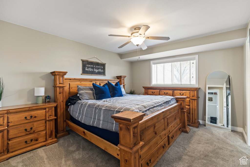Bedroom with a ceiling fan, arched walkways, light carpet, and baseboards