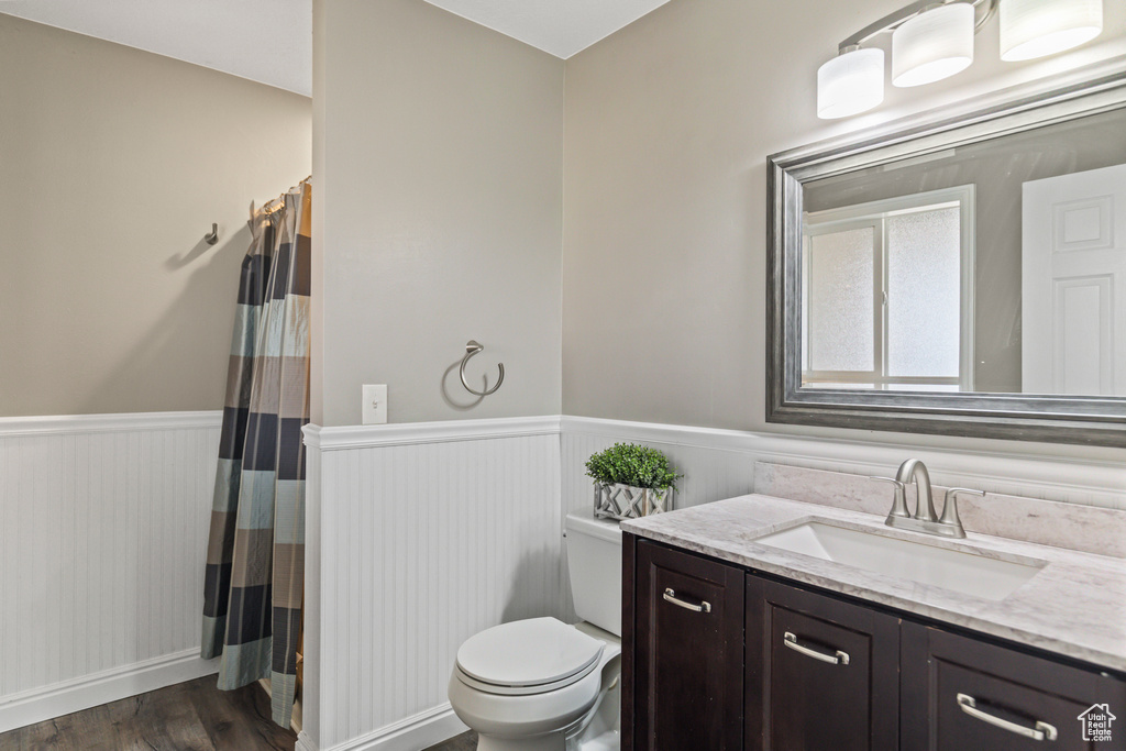 Bathroom with toilet, wainscoting, vanity, wood finished floors, and a shower with curtain