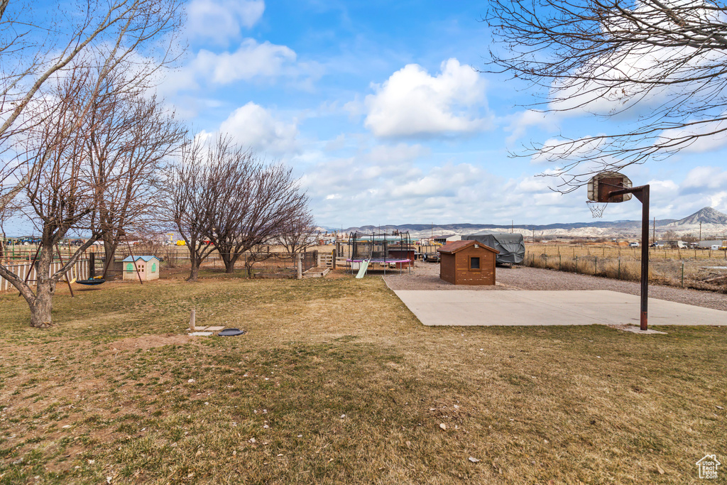 View of yard featuring a fenced backyard, a trampoline, a shed, and an outdoor structure