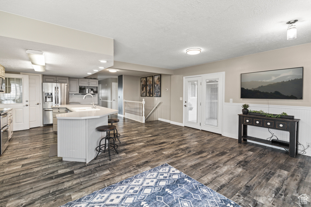 Kitchen with dark wood-style floors, light countertops, appliances with stainless steel finishes, a sink, and a textured ceiling