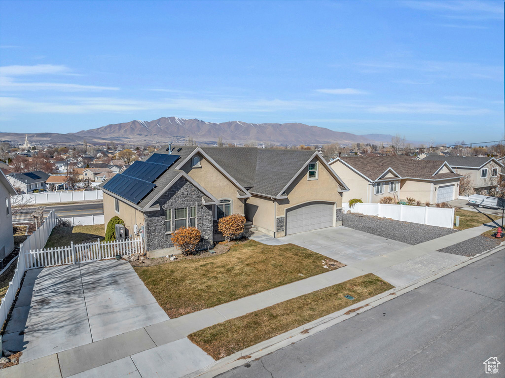 View of front of home featuring fence, concrete driveway, roof mounted solar panels, a residential view, and stucco siding
