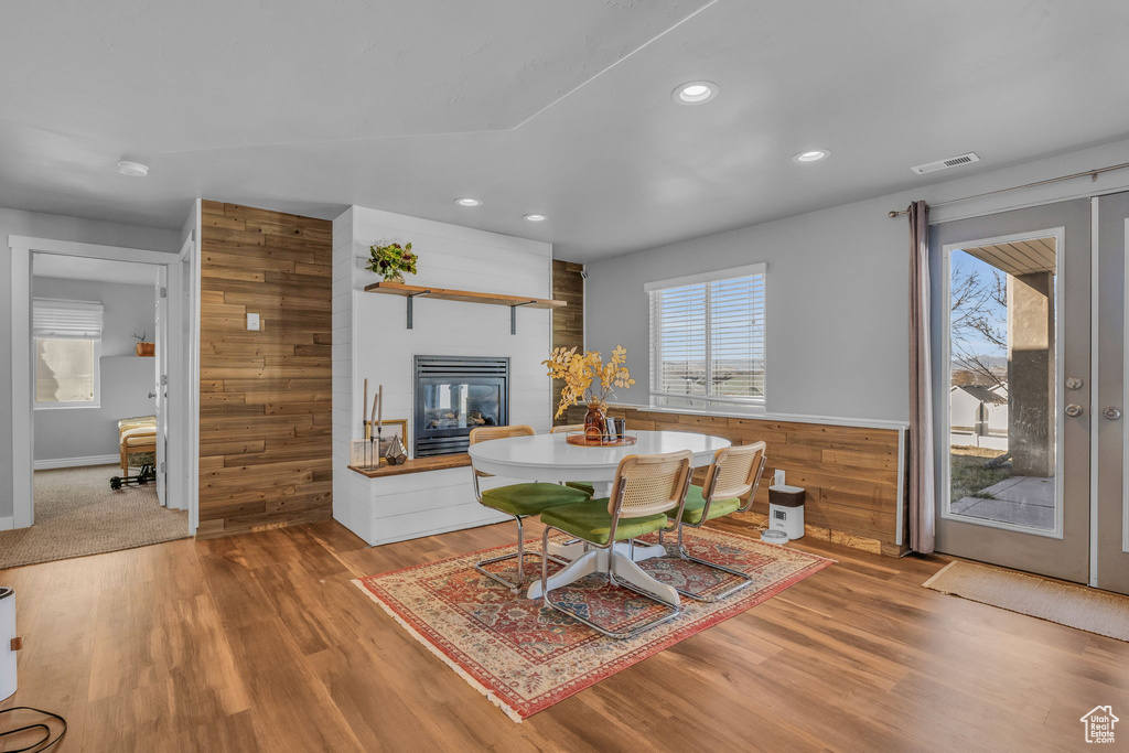 Dining space featuring recessed lighting, visible vents, light wood-style floors, wood walls, and a multi sided fireplace