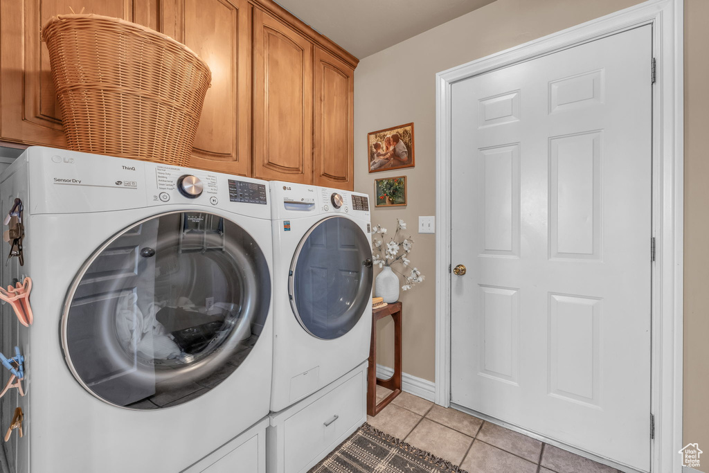 Laundry area featuring cabinet space, light tile patterned floors, baseboards, and independent washer and dryer