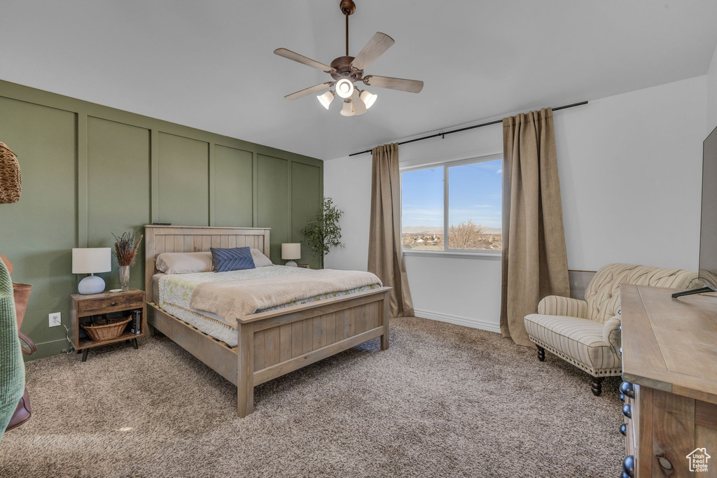 Bedroom with ceiling fan, carpet, and a decorative wall