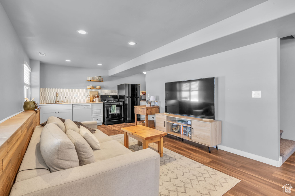 Living room featuring visible vents, baseboards, wood finished floors, wet bar, and recessed lighting