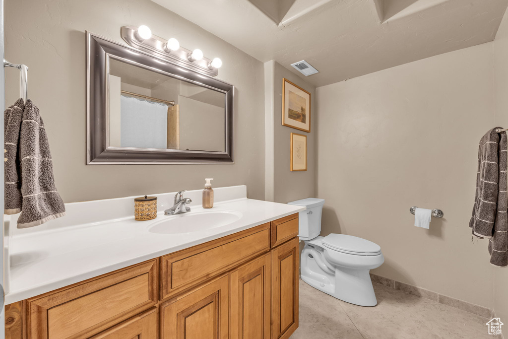 Full bath featuring toilet, vanity, visible vents, and tile patterned floors