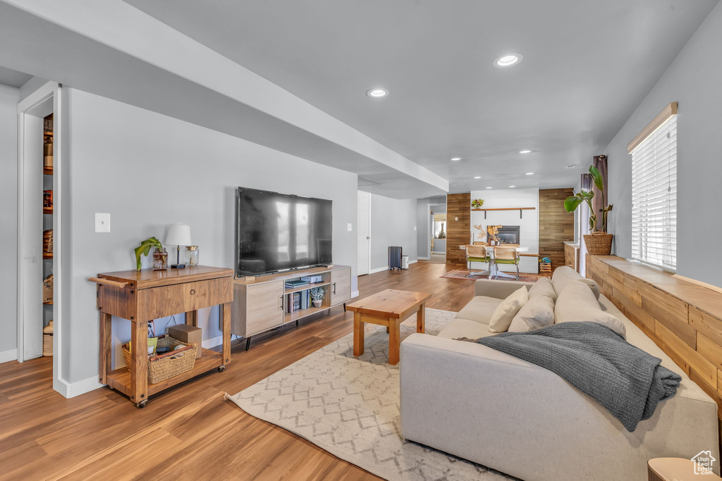 Living room with baseboards, a fireplace, wood finished floors, and recessed lighting