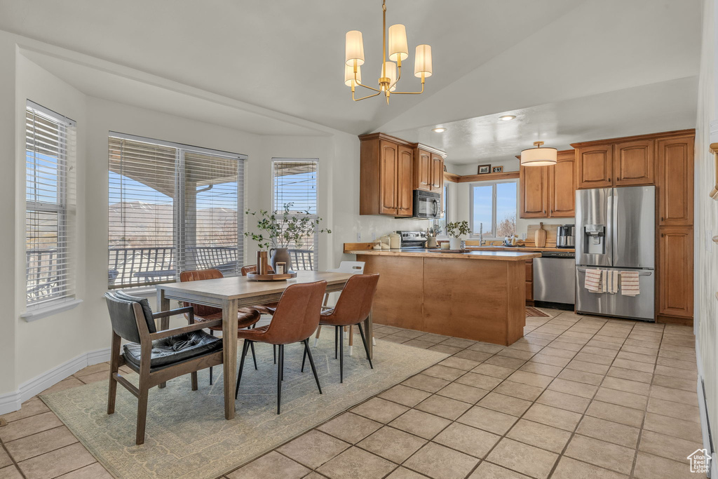 Dining area with a chandelier, a wealth of natural light, vaulted ceiling, and light tile patterned floors