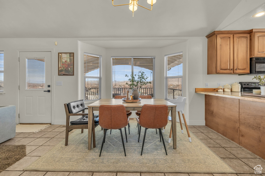 Dining room with light tile patterned floors, baseboards, and an inviting chandelier