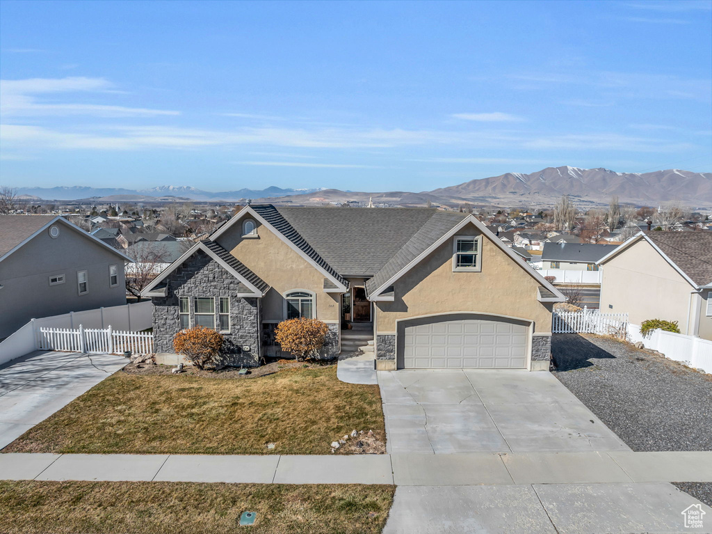 View of front of house with fence, a mountain view, concrete driveway, and stucco siding