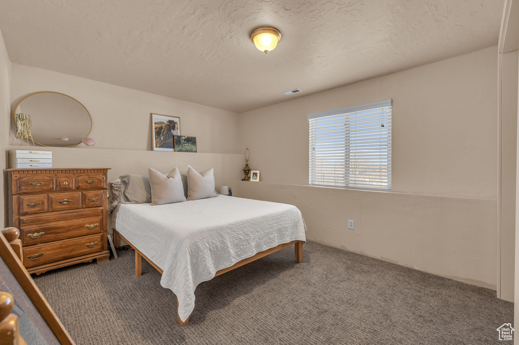 Bedroom with carpet, visible vents, and a textured ceiling