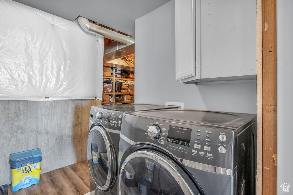 Clothes washing area featuring cabinet space, separate washer and dryer, and wood finished floors
