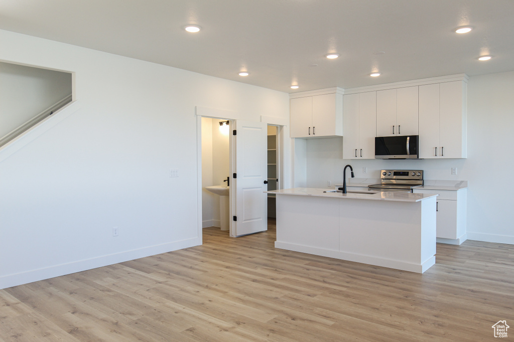 Kitchen with light wood-style floors, white cabinetry, appliances with stainless steel finishes, and recessed lighting