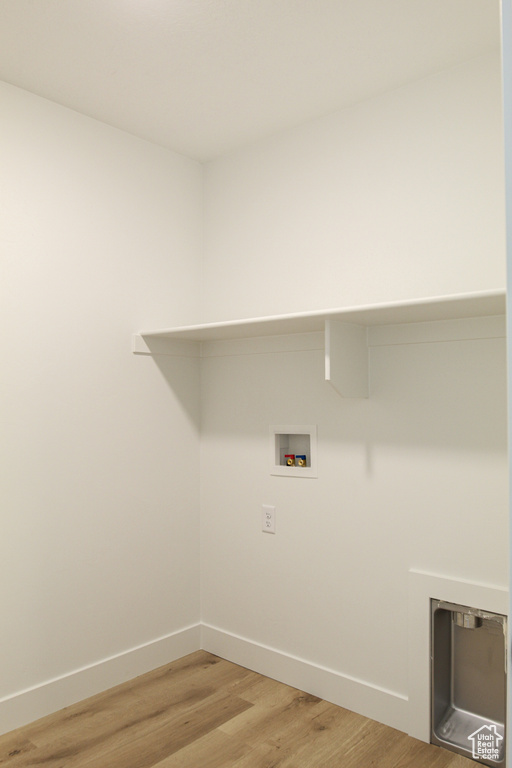 Laundry area featuring laundry area, hookup for a washing machine, baseboards, and light wood-style floors