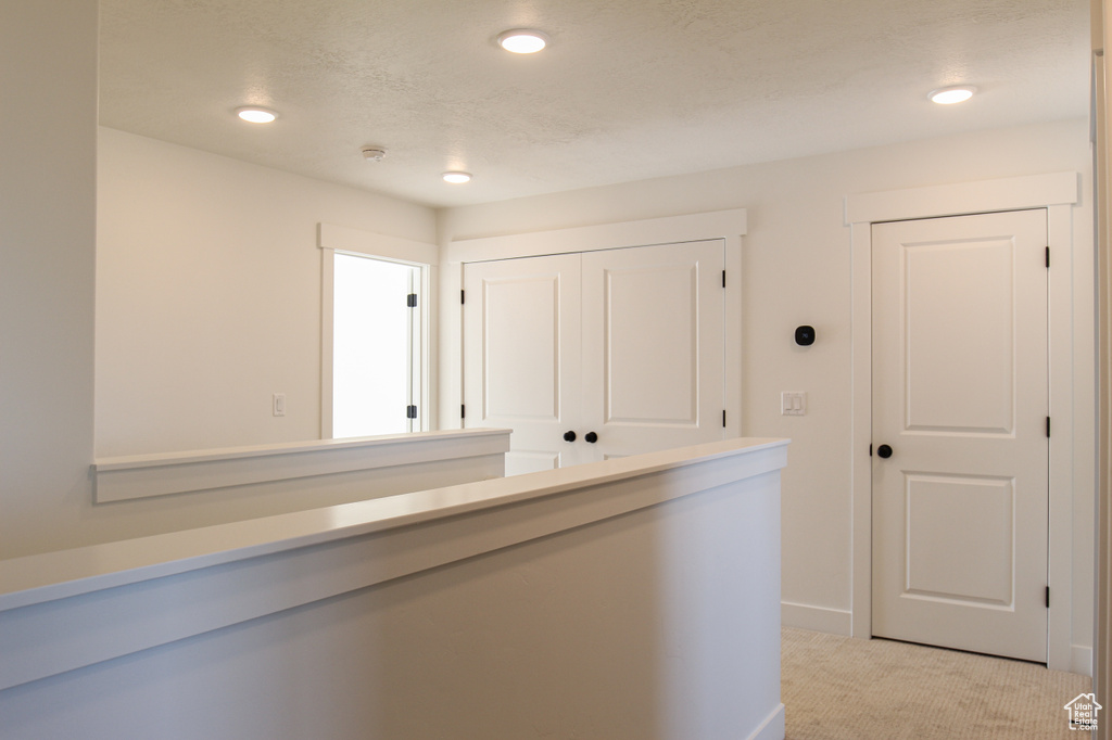 Corridor with recessed lighting, light colored carpet, and baseboards