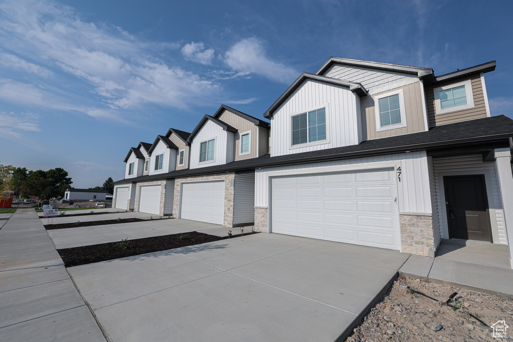 Exterior space with board and batten siding, stone siding, driveway, and a garage