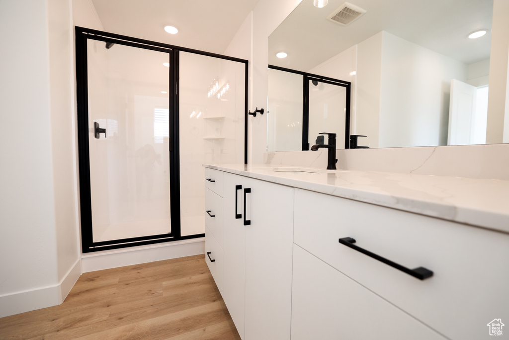 Full bath featuring visible vents, wood finished floors, vanity, a shower stall, and recessed lighting