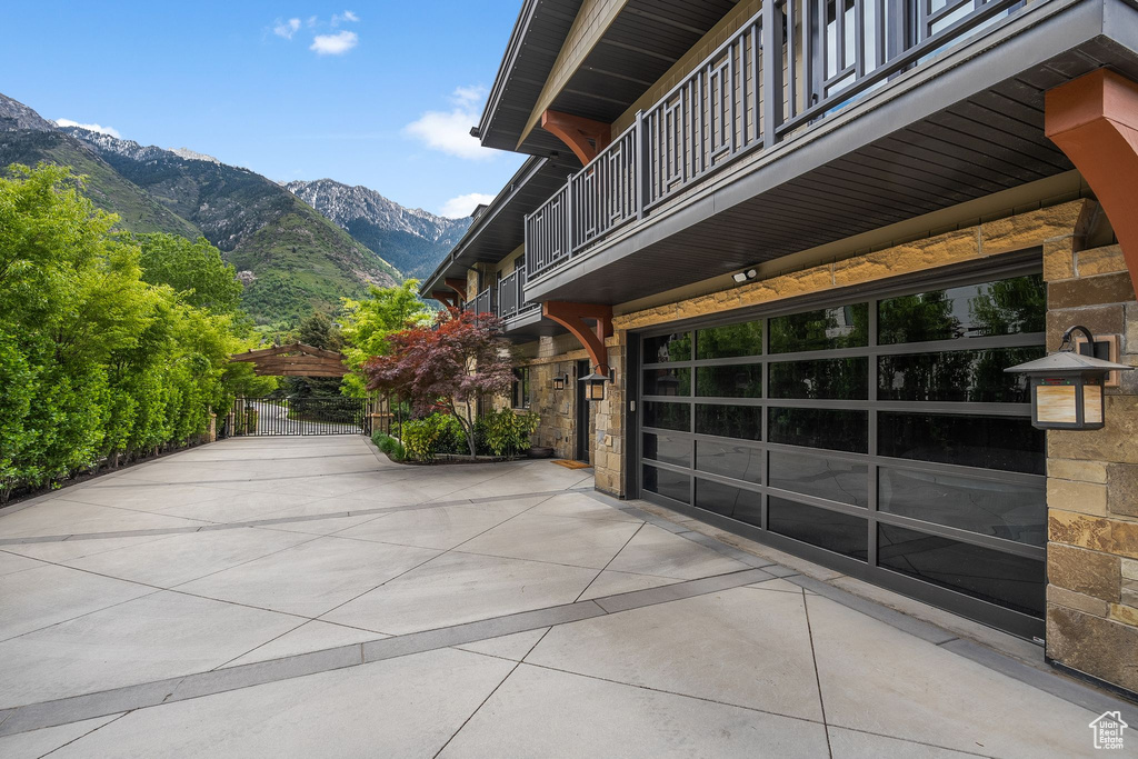 View of patio / terrace featuring a balcony, concrete driveway, a mountain view, and a garage
