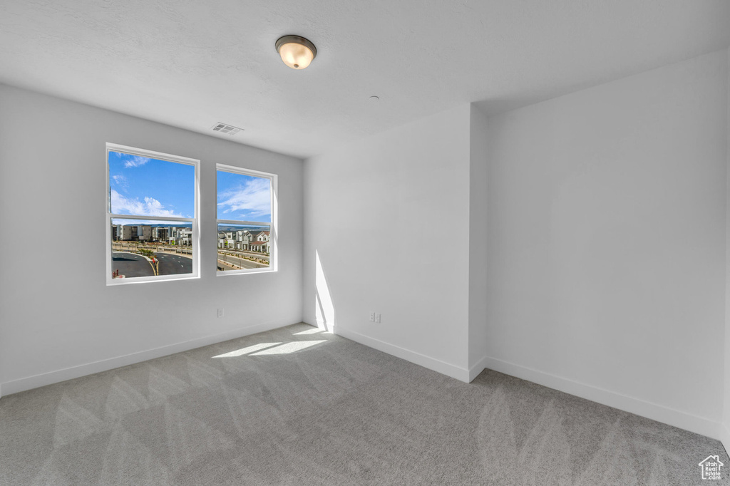 Unfurnished room featuring carpet, visible vents, and baseboards