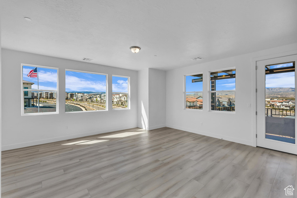 Empty room with plenty of natural light, light wood-style flooring, and visible vents