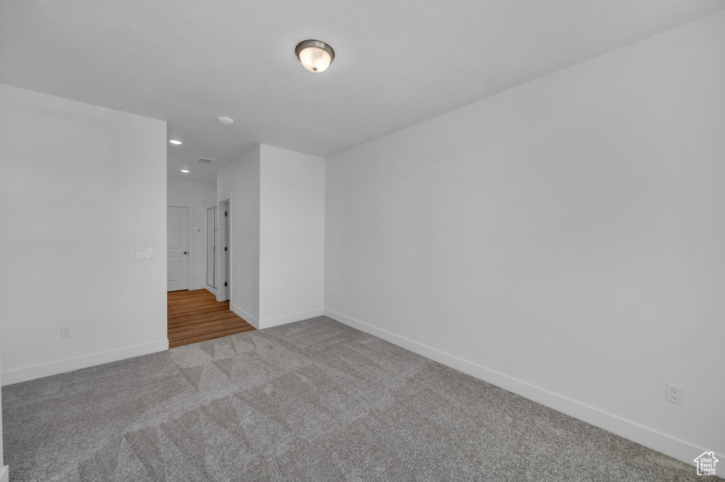 Carpeted empty room featuring visible vents, baseboards, and recessed lighting