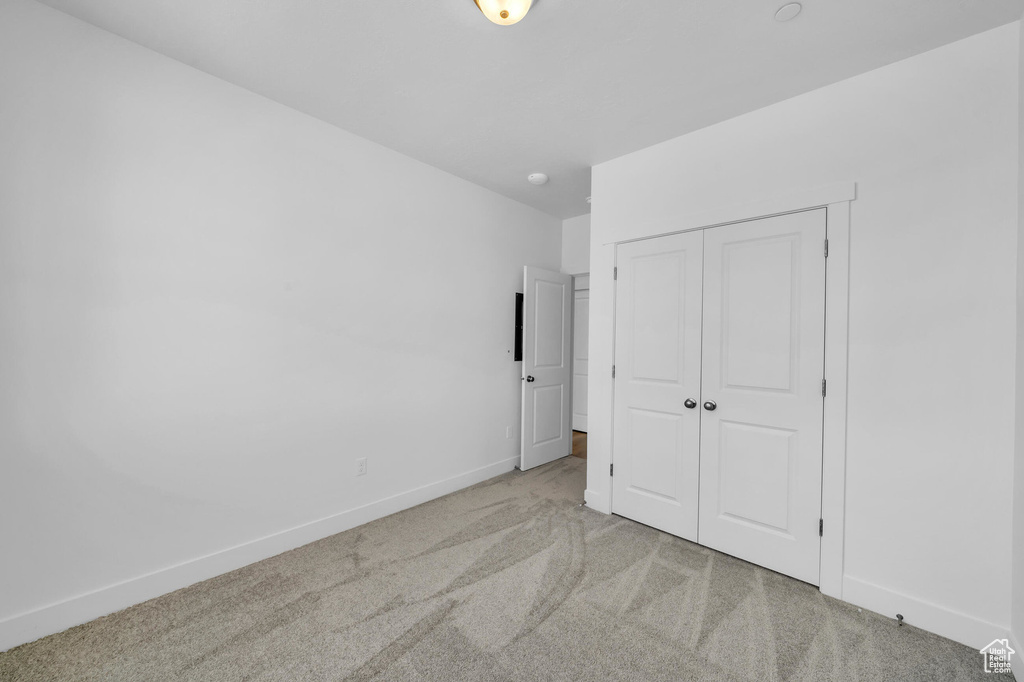 Unfurnished bedroom featuring a closet, baseboards, and carpet flooring