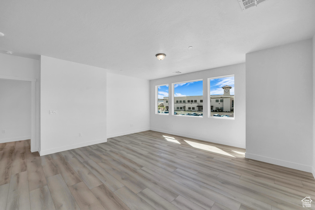 Unfurnished room featuring visible vents, baseboards, and wood finished floors