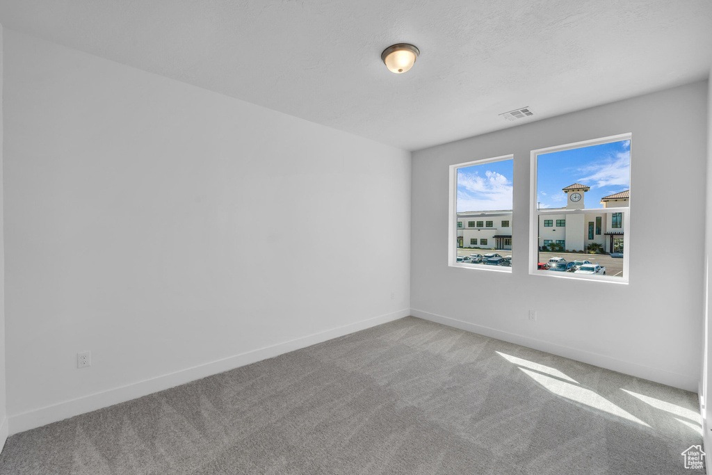 Carpeted spare room with visible vents and baseboards