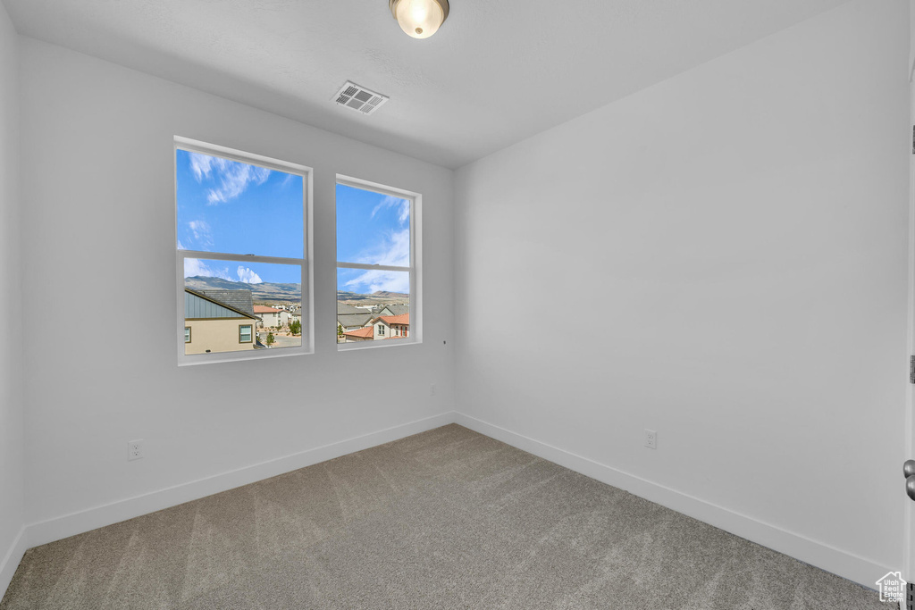 Carpeted spare room featuring visible vents and baseboards