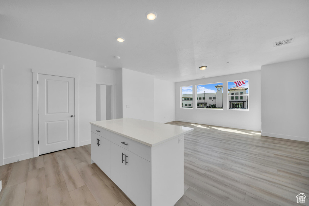 Kitchen featuring light wood-style floors, visible vents, a kitchen island, and white cabinetry