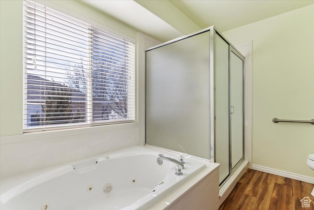 Bathroom featuring a shower stall, a whirlpool tub, and wood finished floors