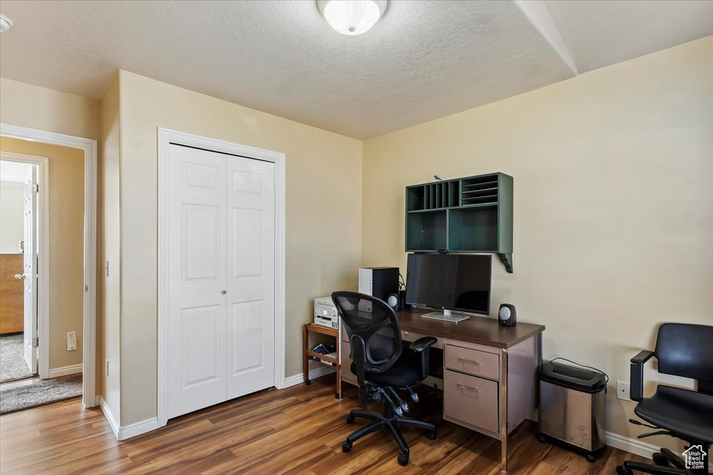 Office space featuring a textured ceiling, baseboards, and wood finished floors