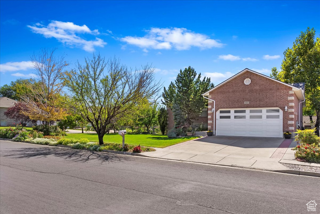 View of front of home with a front yard, concrete driveway, brick siding, and an attached garage