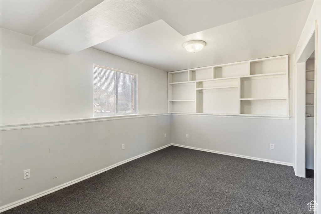 Spare room with baseboards and dark colored carpet