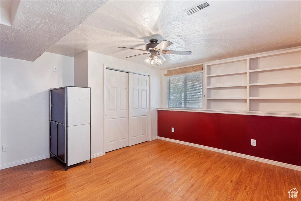 Unfurnished bedroom featuring light wood-type flooring, baseboards, visible vents, and a textured ceiling