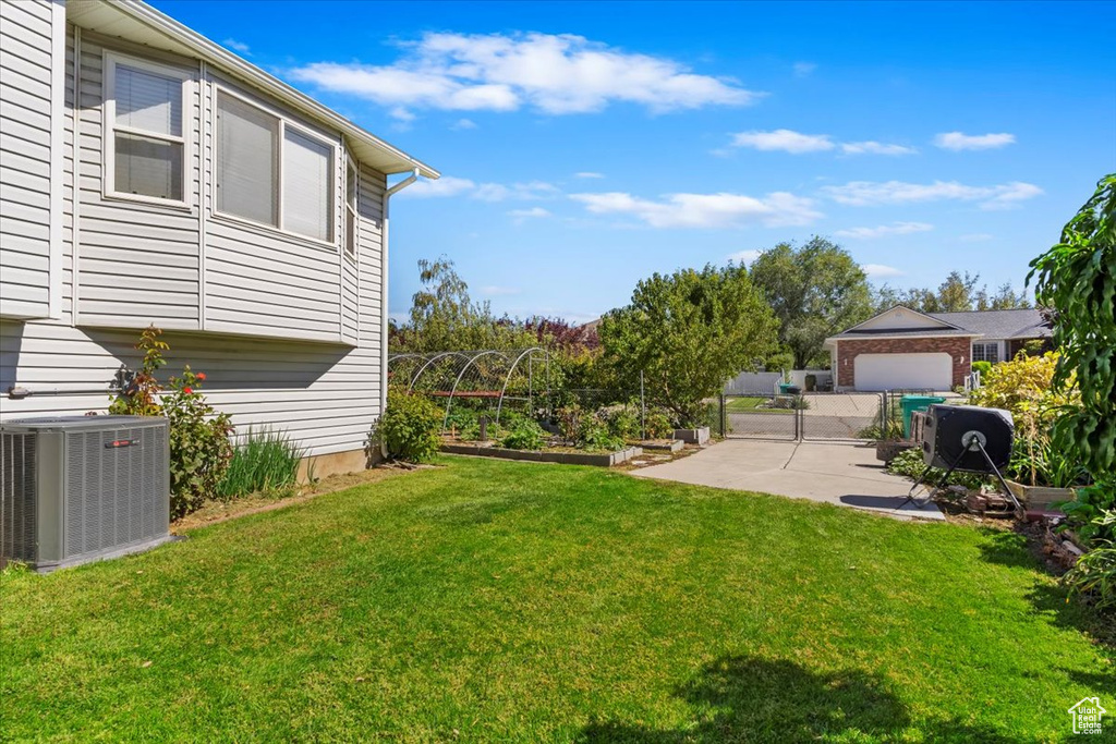View of yard featuring central AC unit, a patio area, a vegetable garden, and fence