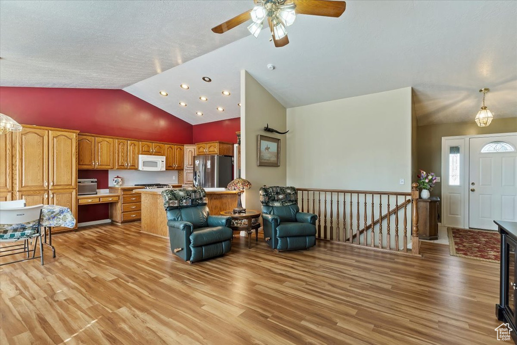 Living area featuring vaulted ceiling, ceiling fan, and light wood-type flooring