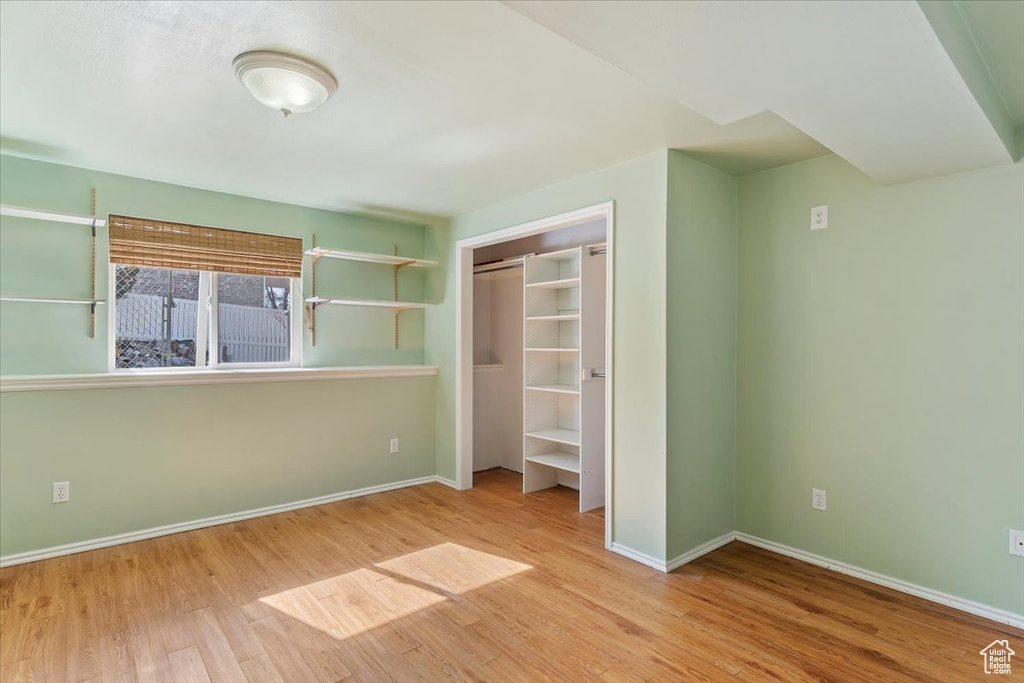 Unfurnished bedroom featuring a closet, wood finished floors, and baseboards
