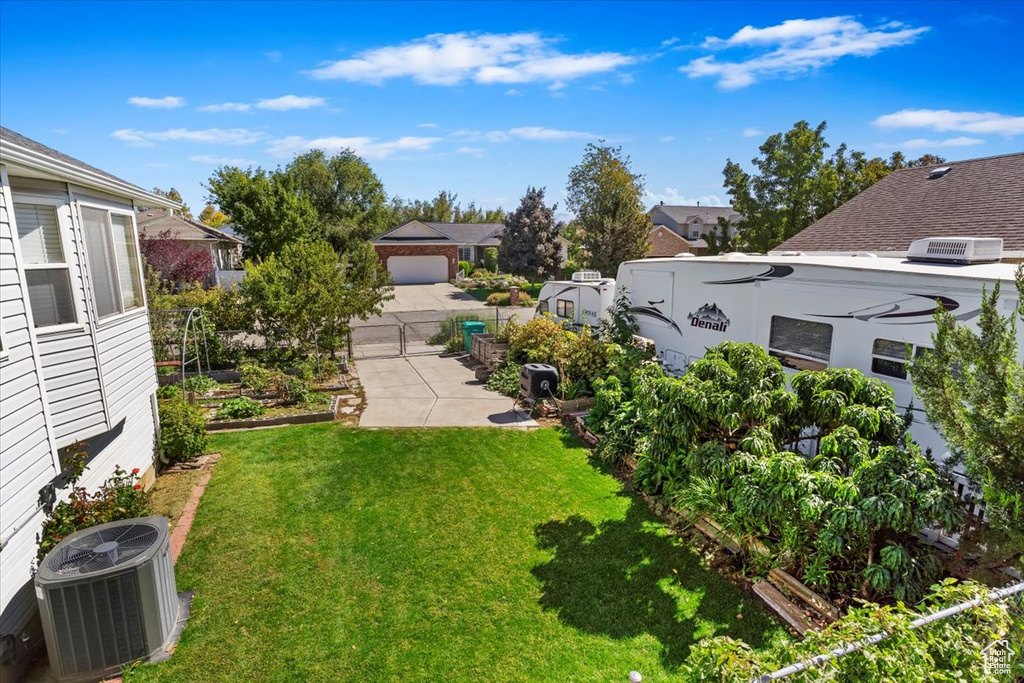 View of yard featuring a vegetable garden, a gate, fence, and cooling unit