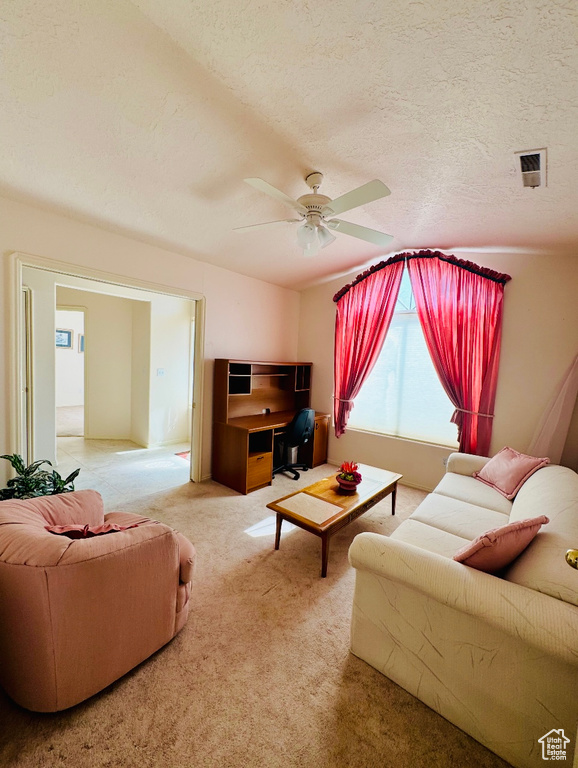 Carpeted living room featuring a ceiling fan and a textured ceiling