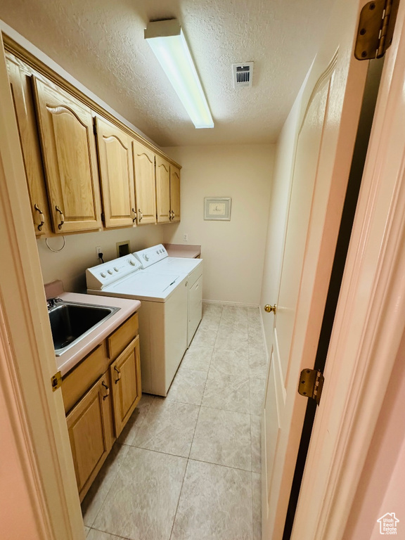 Laundry area featuring cabinet space, independent washer and dryer, a textured ceiling, and light tile patterned flooring