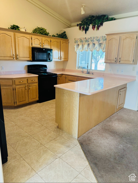 Kitchen featuring black appliances, a sink, a peninsula, light countertops, and lofted ceiling