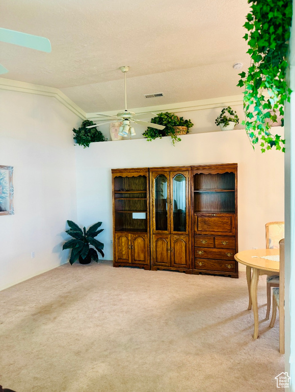 Living area featuring carpet flooring, a ceiling fan, crown molding, and lofted ceiling