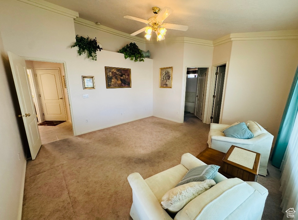 Living area with ceiling fan, light carpet, crown molding, and baseboards